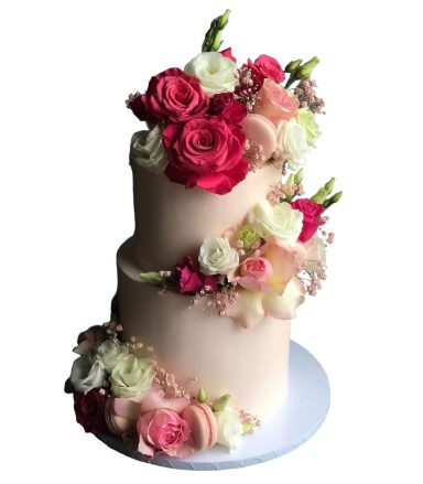 Zweistöckige Torte mit rosa und weißen Blumen dekoriert.